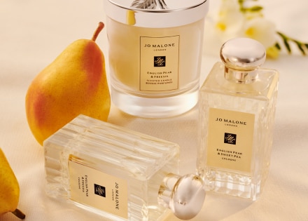 Colognes English Pear and Freesia y vela sobre una mesa, con una pera