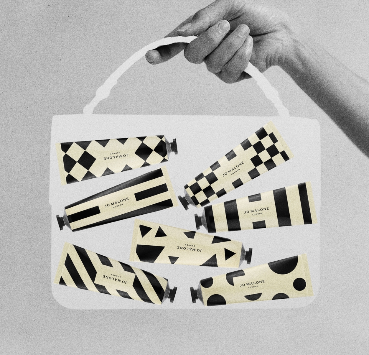 Imagen en negro, blanco y crema de una bolsa transparente mediana sostenida en una mano, que contiene siete cremas de manos en envases estampados.